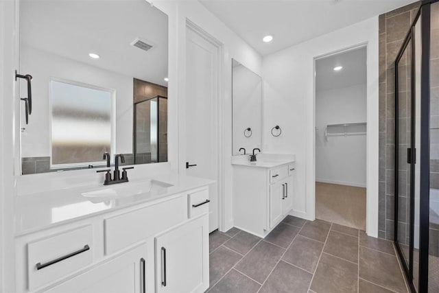 5804 Kelly Kyle Ave, Georgetown, TX 78628 - bathroom featuring a stall shower, two vanities, a spacious closet, recessed lighting, and tile patterned flooring