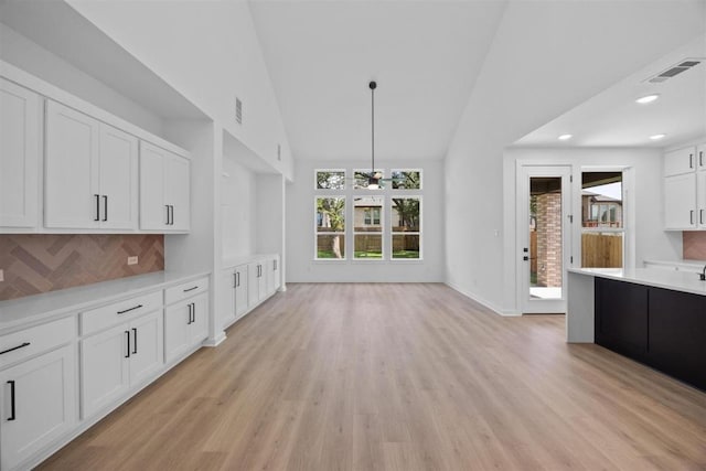 5804 Kelly Kyle Ave, Georgetown, TX 78628 - kitchen featuring light countertops, white cabinetry, light wood-style flooring, backsplash, and high vaulted ceiling