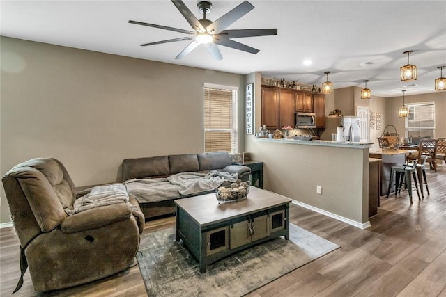 living area with a healthy amount of sunlight, ceiling fan, baseboards, and wood finished floors