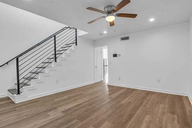 unfurnished living room featuring stairs, visible vents, baseboards, and wood finished floors