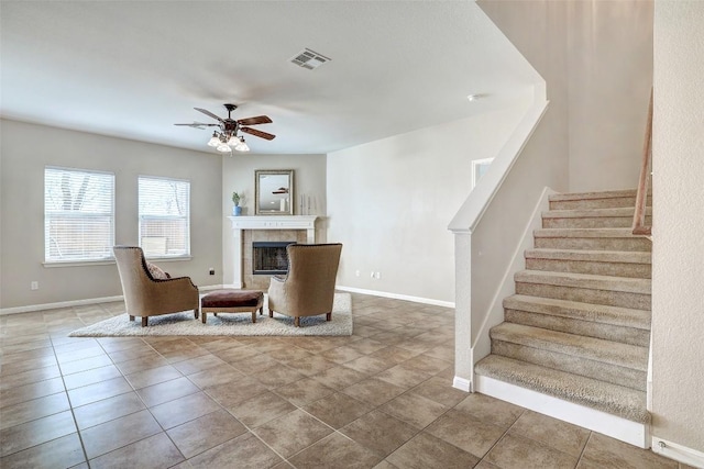 living area with a fireplace, visible vents, stairway, a ceiling fan, and baseboards