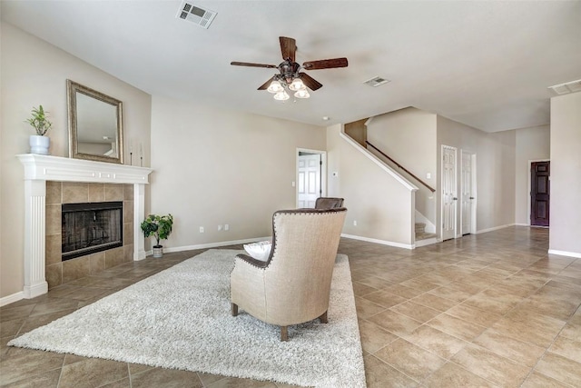 sitting room with stairs, visible vents, and a tile fireplace