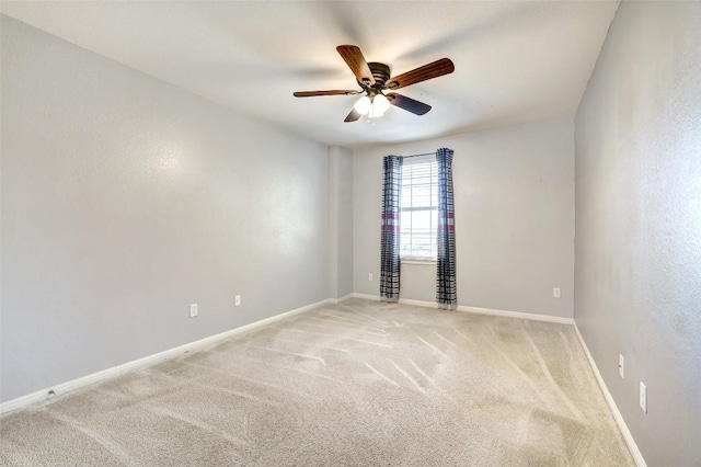 spare room with baseboards, a ceiling fan, and light colored carpet