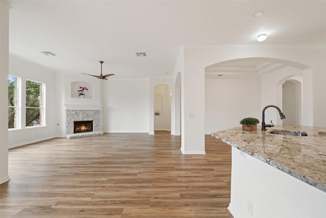 living room featuring a warm lit fireplace, visible vents, and ornamental molding