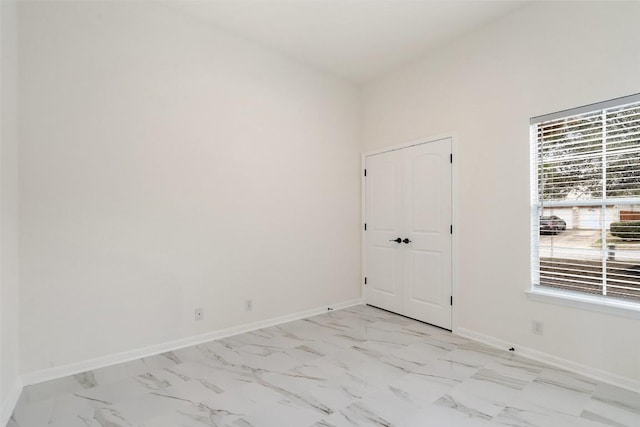 empty room featuring marble finish floor and baseboards