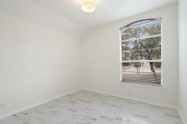 spare room featuring marble finish floor, vaulted ceiling, and baseboards