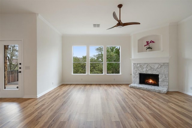 unfurnished living room with baseboards, visible vents, wood finished floors, crown molding, and a fireplace