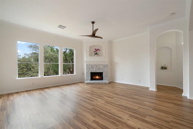 unfurnished living room with ceiling fan, wood finished floors, visible vents, baseboards, and a lit fireplace