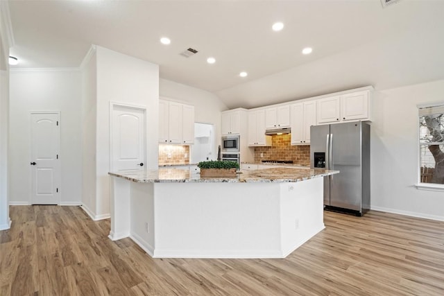 kitchen with light stone counters, appliances with stainless steel finishes, visible vents, and under cabinet range hood