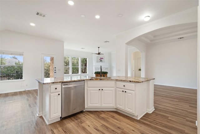 kitchen with arched walkways, light wood-style flooring, a sink, visible vents, and dishwasher