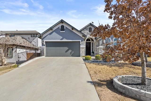 view of front of house featuring stucco siding, fence, a garage, stone siding, and driveway