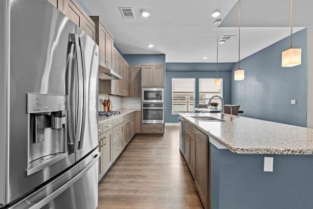 kitchen featuring visible vents, wood finished floors, stainless steel appliances, under cabinet range hood, and a sink