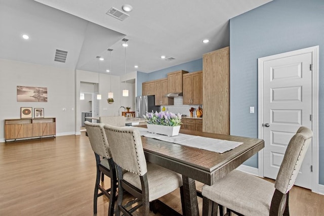 dining room featuring light wood-type flooring, visible vents, and baseboards