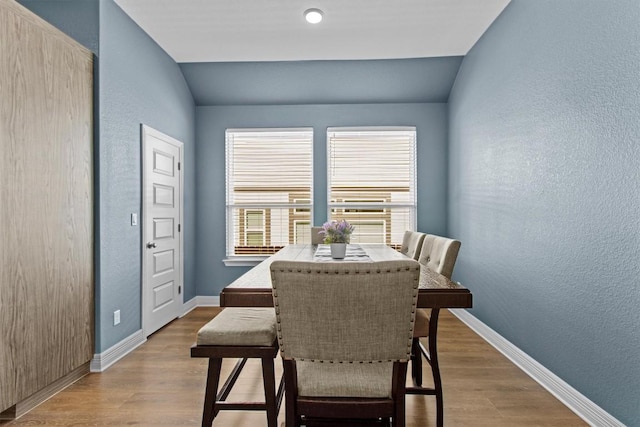 dining room with vaulted ceiling, baseboards, and wood finished floors