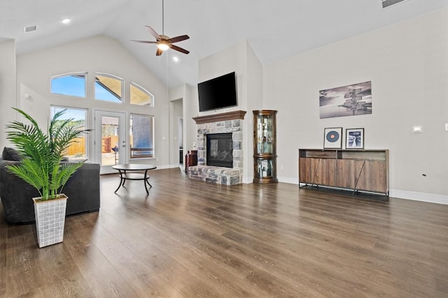 living area with high vaulted ceiling, a stone fireplace, wood finished floors, and visible vents