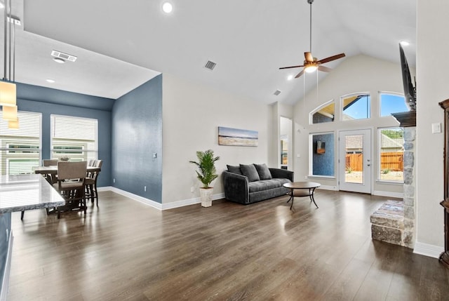 living area with dark wood-type flooring, visible vents, high vaulted ceiling, and baseboards