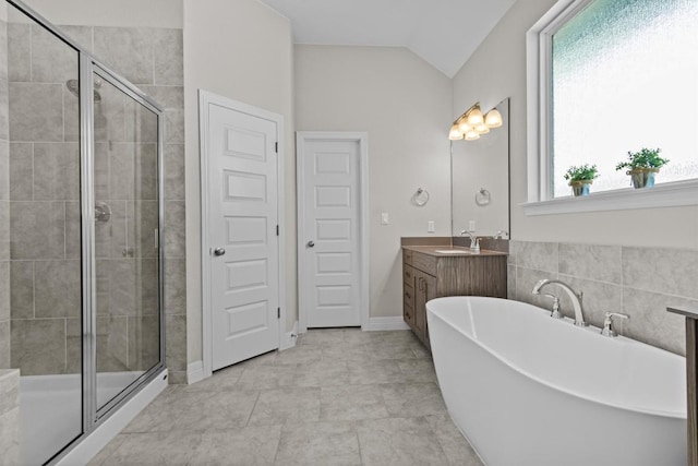 full bathroom featuring a soaking tub, vaulted ceiling, a shower stall, and vanity