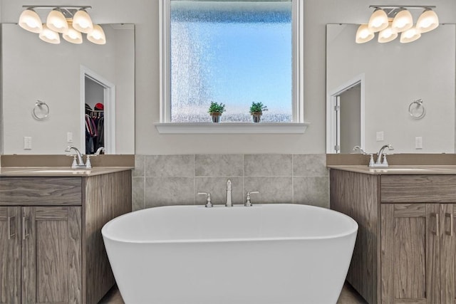 full bath featuring a freestanding tub, two vanities, and a sink