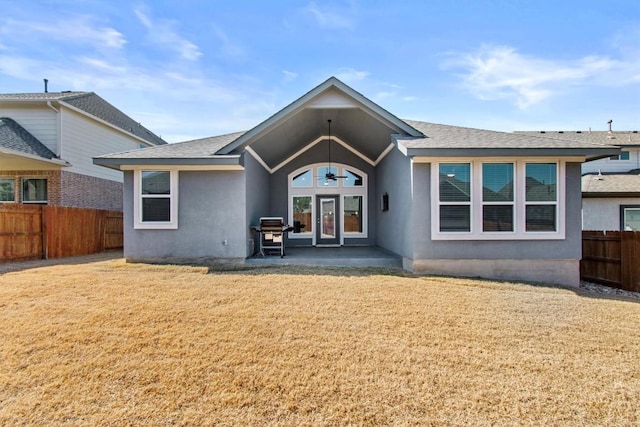 rear view of house featuring french doors, roof with shingles, fence, a yard, and stucco siding