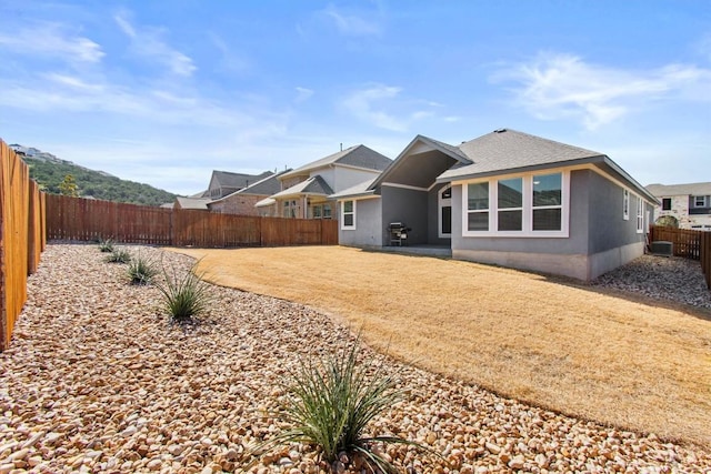 back of house with a shingled roof, a fenced backyard, and stucco siding