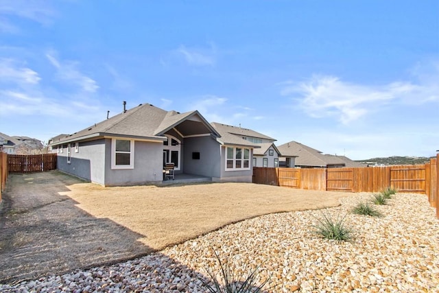 rear view of property featuring a patio, a shingled roof, a fenced backyard, and stucco siding