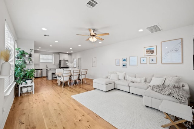 living area with light wood-style floors, ceiling fan, visible vents, and recessed lighting