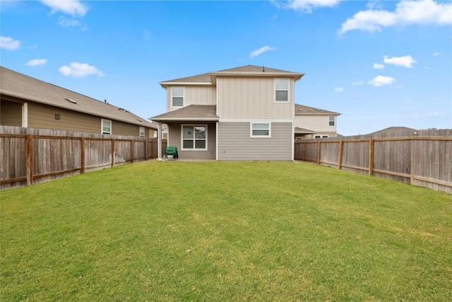 back of house featuring a fenced backyard, board and batten siding, and a yard