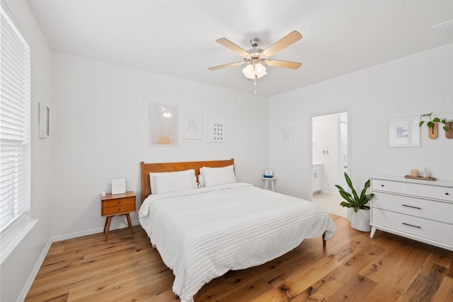 bedroom with light wood finished floors, connected bathroom, a ceiling fan, and baseboards