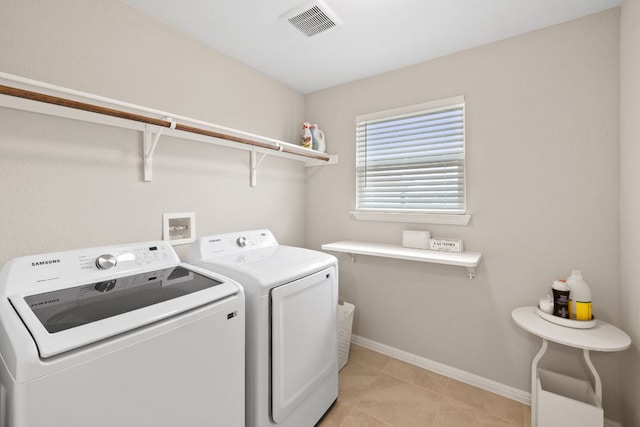 clothes washing area with light tile patterned floors, laundry area, visible vents, baseboards, and independent washer and dryer