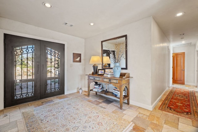 foyer entrance with french doors, stone tile flooring, and baseboards