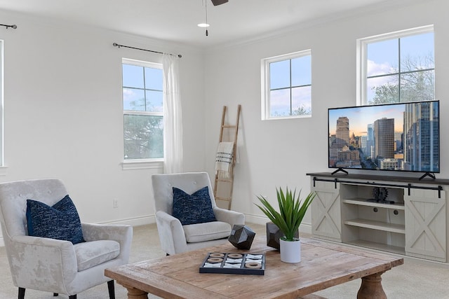 living area featuring carpet floors, baseboards, ornamental molding, and ceiling fan