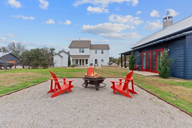 exterior space featuring a fire pit, a patio, french doors, and a lawn