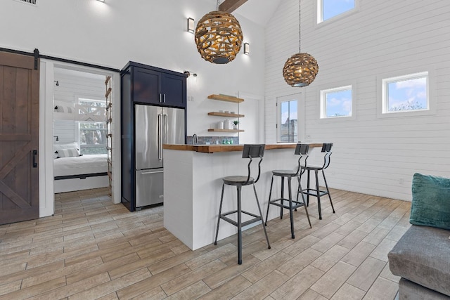 kitchen with high end fridge, a barn door, a breakfast bar, and wood tiled floor