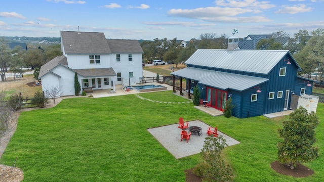 back of property with an outdoor fire pit, a patio area, a yard, and a chimney