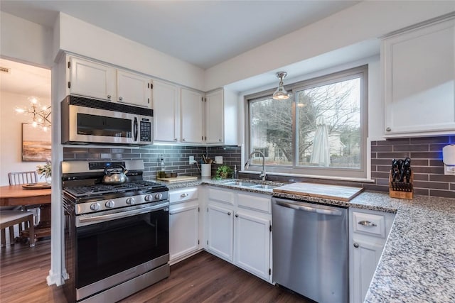 kitchen with light stone counters, appliances with stainless steel finishes, white cabinets, and a sink