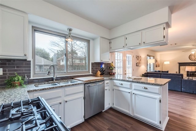 kitchen with a peninsula, stainless steel dishwasher, a sink, and white cabinets