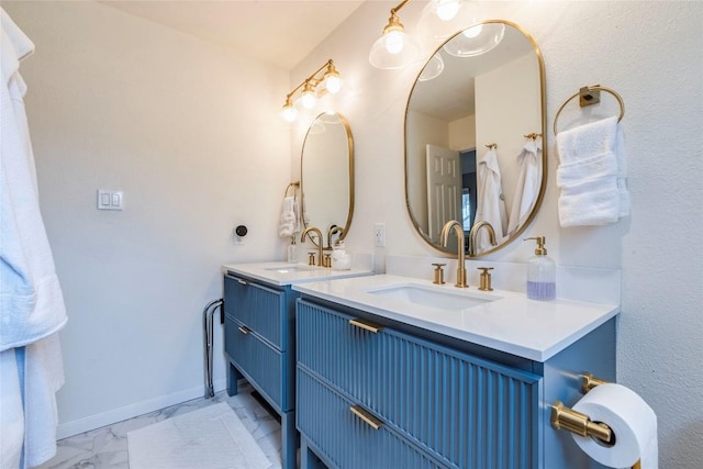 bathroom with marble finish floor, vanity, and baseboards