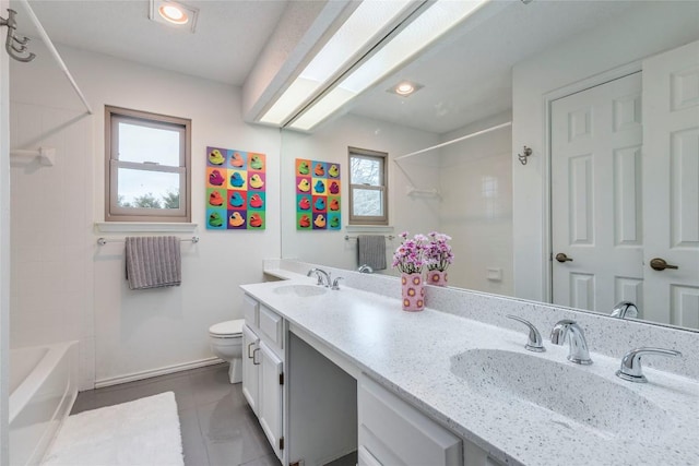 bathroom with toilet, double vanity, tub / shower combination, and a sink