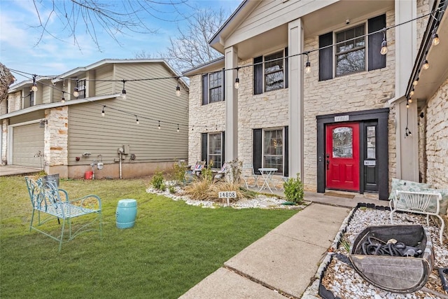 property entrance featuring stone siding, a lawn, and an attached garage