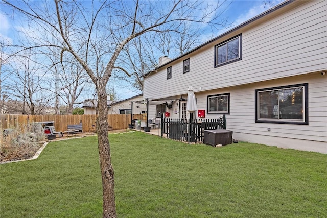 rear view of property with a chimney, fence, a lawn, and a patio