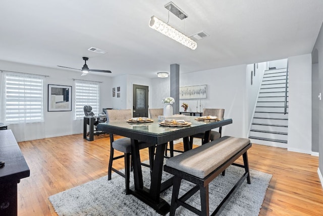 dining room featuring light wood finished floors, baseboards, stairway, and visible vents