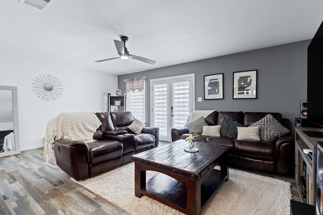 living area with light wood-style floors, ceiling fan, and visible vents