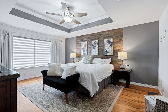 bedroom with an accent wall, a raised ceiling, and baseboards