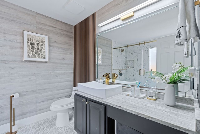 bathroom with toilet, vanity, tile walls, a marble finish shower, and tile patterned floors