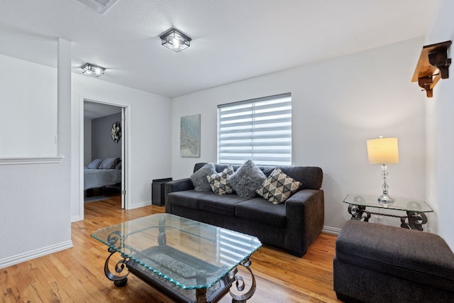 living area featuring light wood-style floors, visible vents, and baseboards