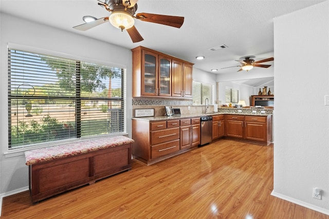 kitchen with visible vents, dishwasher, glass insert cabinets, light wood-type flooring, and a sink