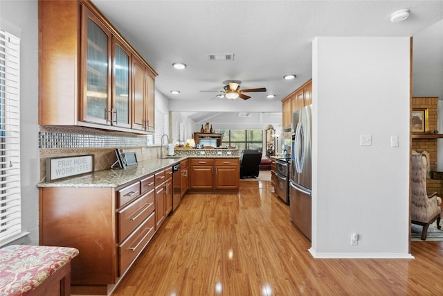 kitchen featuring stainless steel appliances, visible vents, a sink, light wood-type flooring, and a peninsula