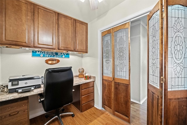 home office with built in desk, light wood-type flooring, a ceiling fan, and baseboards