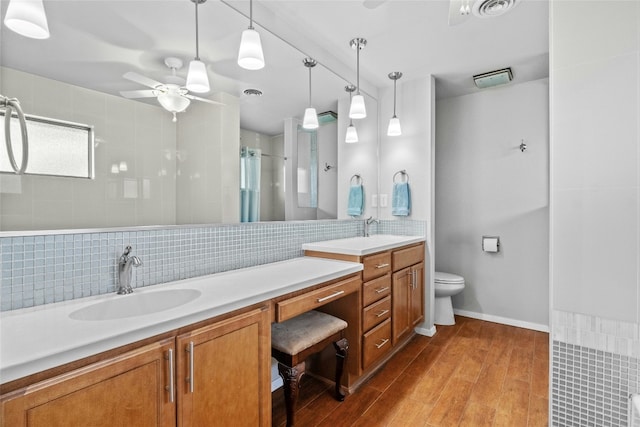 bathroom with a tile shower, a sink, backsplash, and wood finished floors