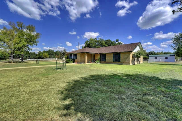 view of front facade featuring brick siding, fence, and a front lawn